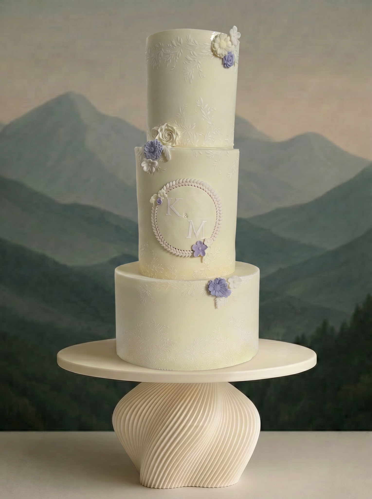 Three-tier ivory wedding cake with delicate embossed fondant floral flowers, and a central monogram plaque
